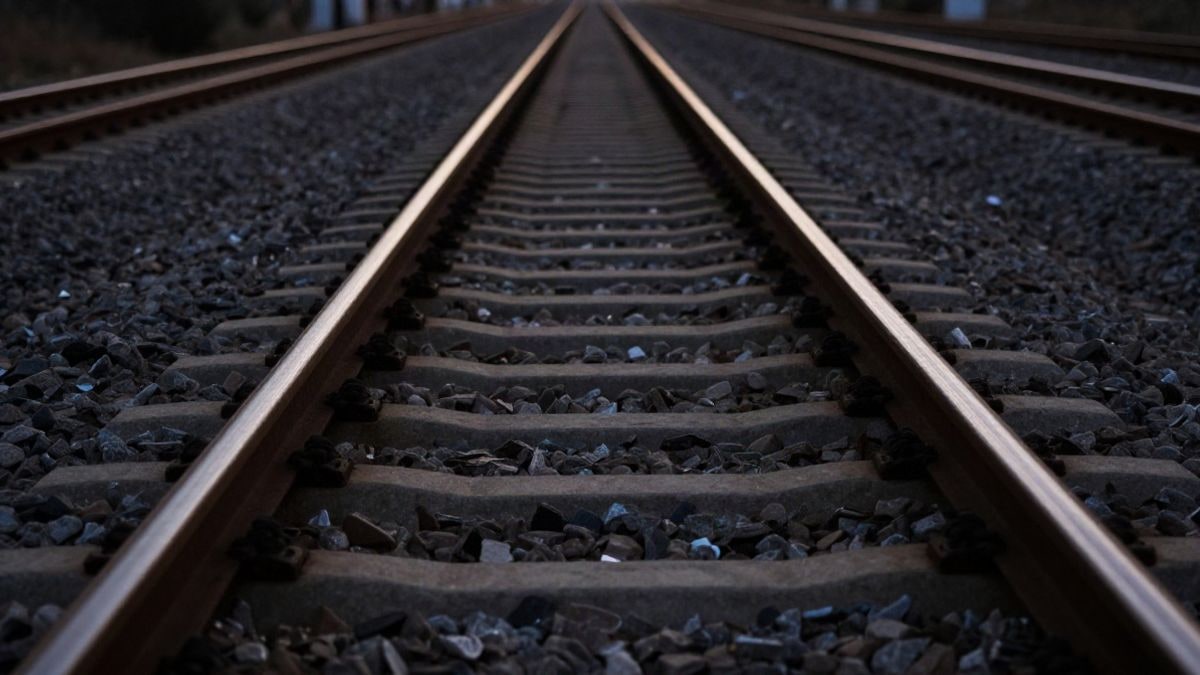 Imagen ilustrativa: vía de tren al atardecer con raíles en primer plano y fondo desenfocado