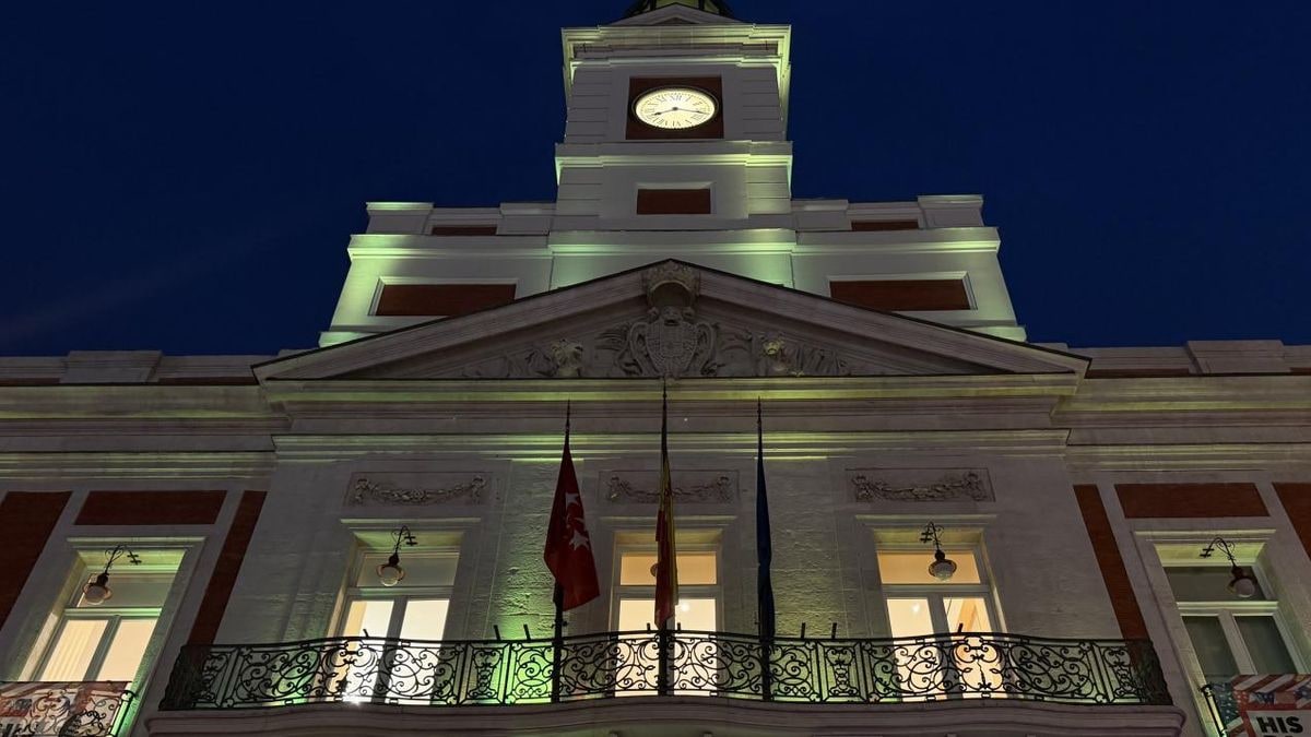 Imagen ilustrativa: fachada de un edificio institucional iluminada de verde al atardecer en una plaza vacía
