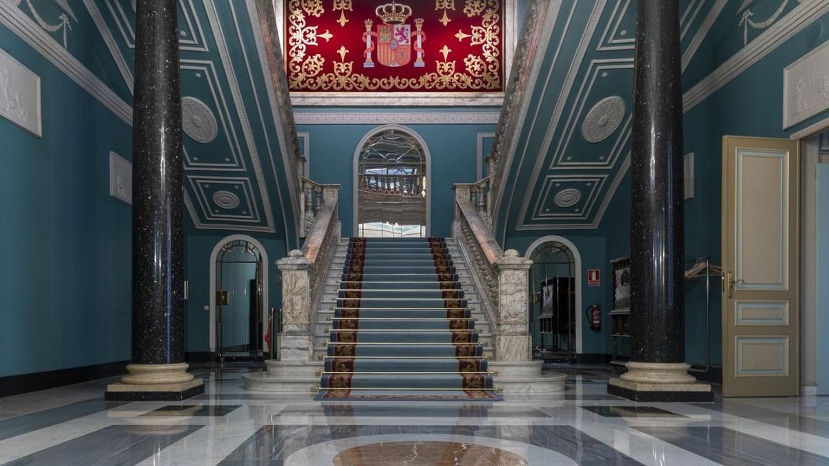 Imagen ilustrativa: interior de un salón palaciego con lámparas de cristal y detalles dorados, con luz natural entrando por grandes ventanales.