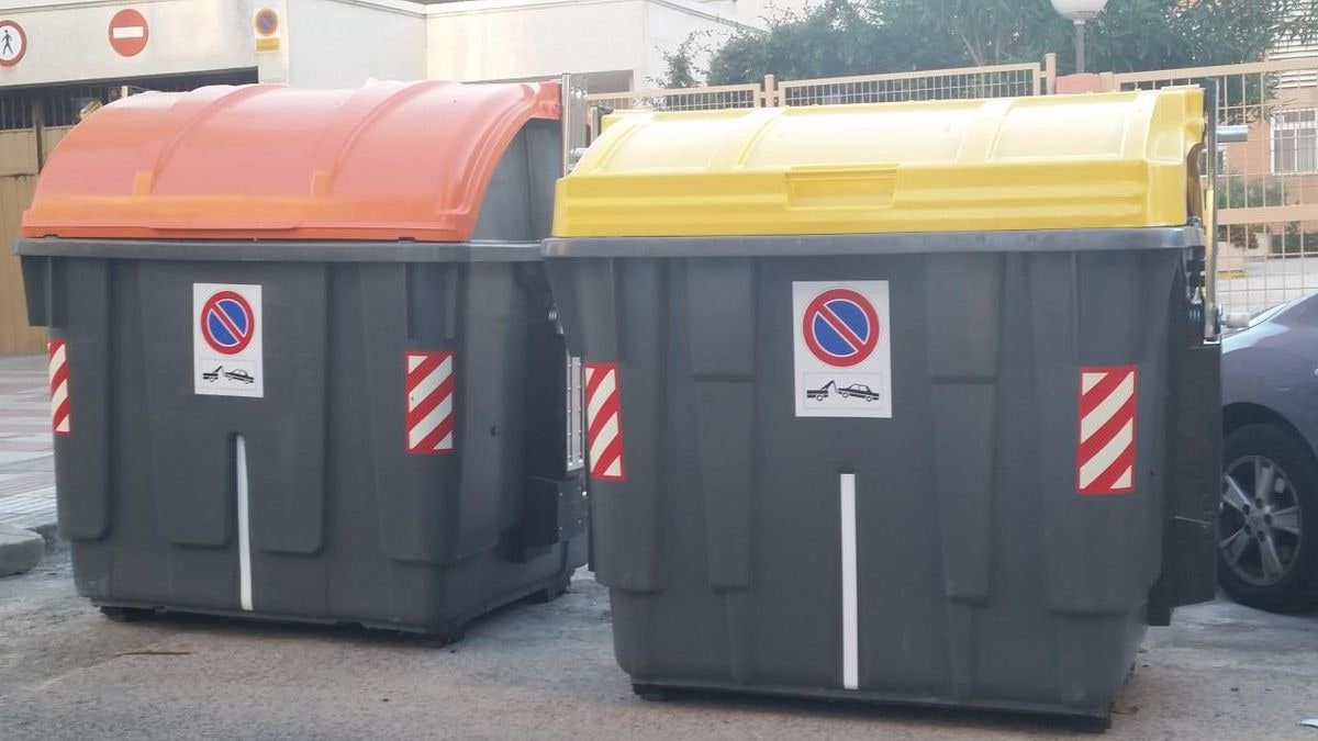 Imagen ilustrativa: fila de contenedores municipales de basura en una carretera rural al atardecer