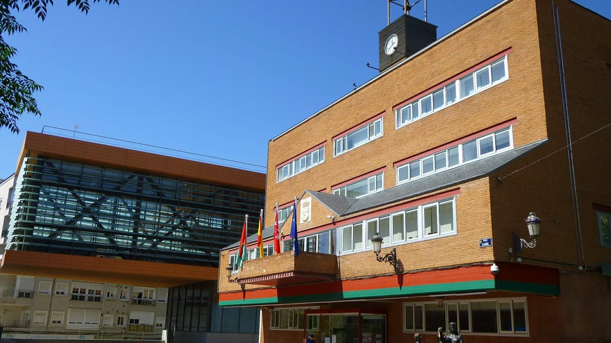 Fachada del Ayuntamiento de Alcorcón con banderas, reloj en la torre y edificio de cristal al lado