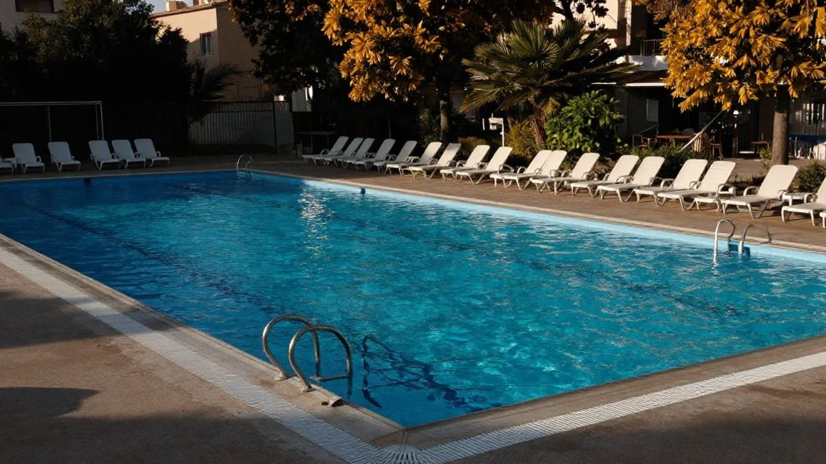 Imagen ilustrativa: piscina municipal al aire libre vacía, con el agua en calma y tumbonas a la luz del atardecer