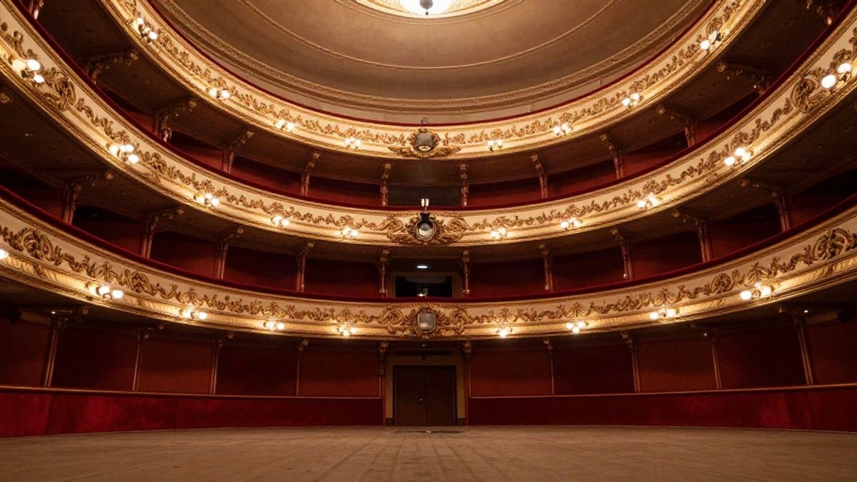 Imagen ilustrativa: un escenario de teatro con cortinas rojas y palcos dorados, visto desde el patio de butacas