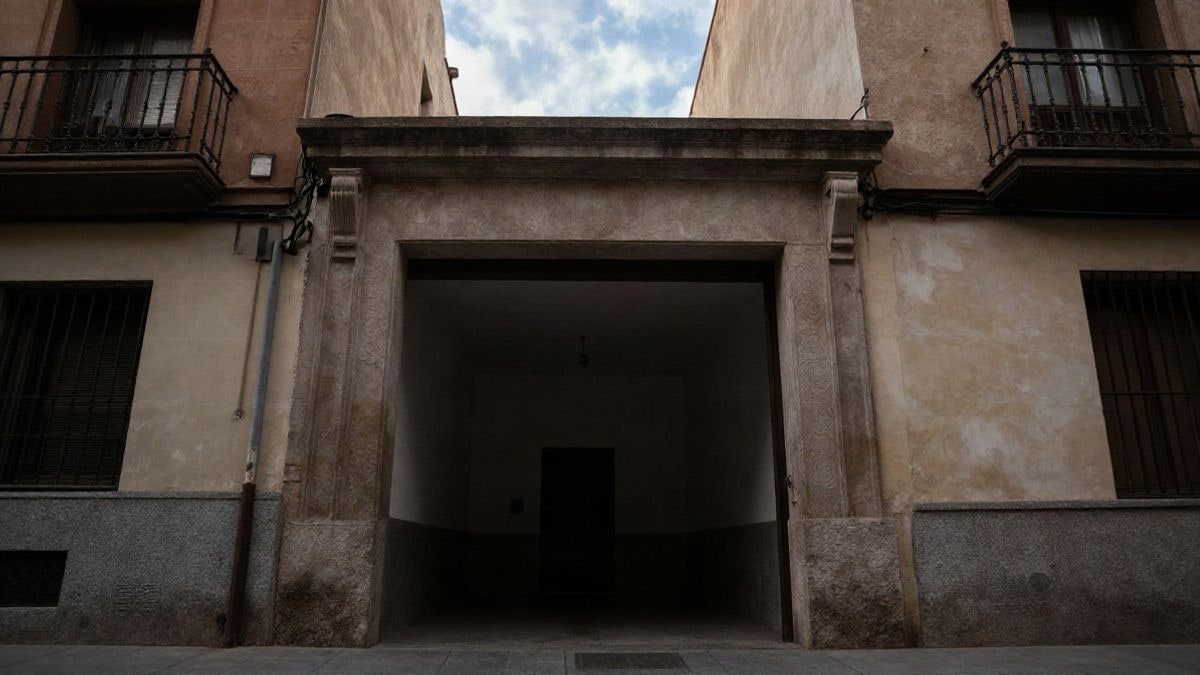 Imagen ilustrativa: ángulo bajo a ras de suelo con cielo de fondo de la entrada de un edificio residencial vacío en una ciudad española