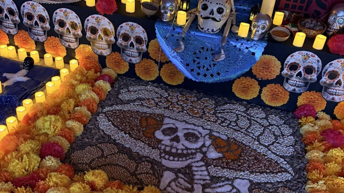 Imagen ilustrativa: velas encendidas y flores de cempasúchil sobre una mesa de madera en una estancia en penumbra