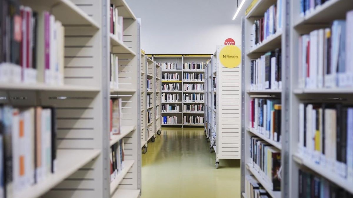 Imagen ilustrativa: sala de lectura de una biblioteca pública con estanterías y una mesa con un libro abierto