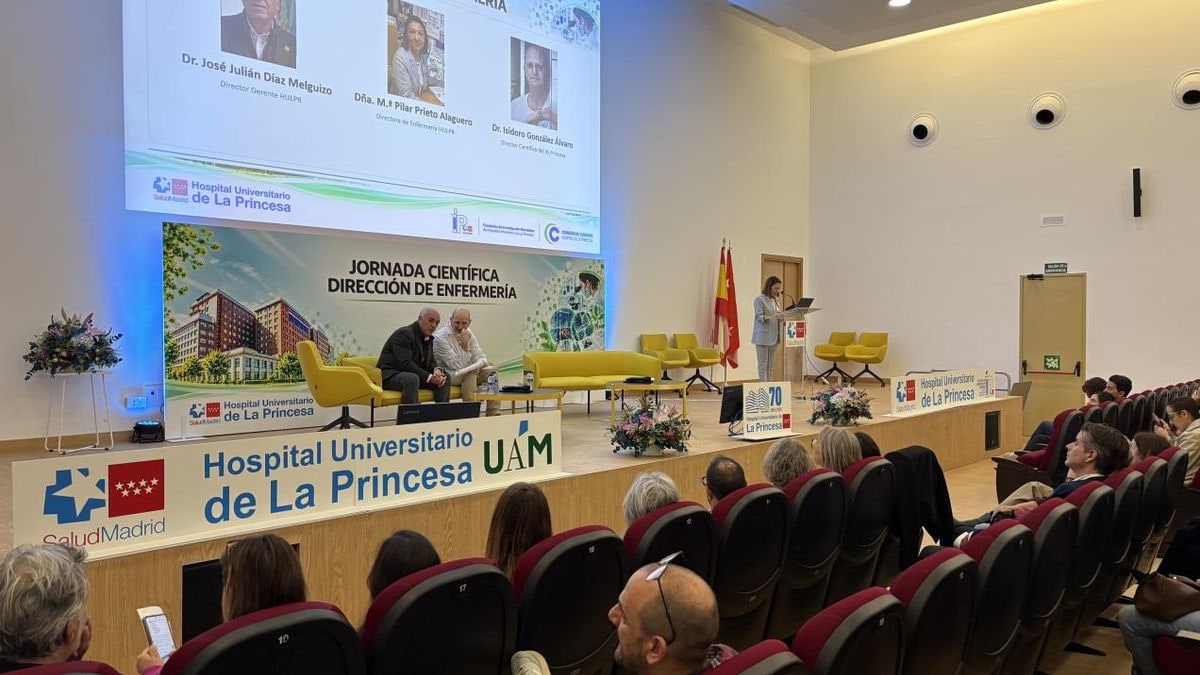 Imagen ilustrativa: sala de conferencias de un hospital vacía, con sillas en filas y una mesa iluminada por la luz de una ventana lateral