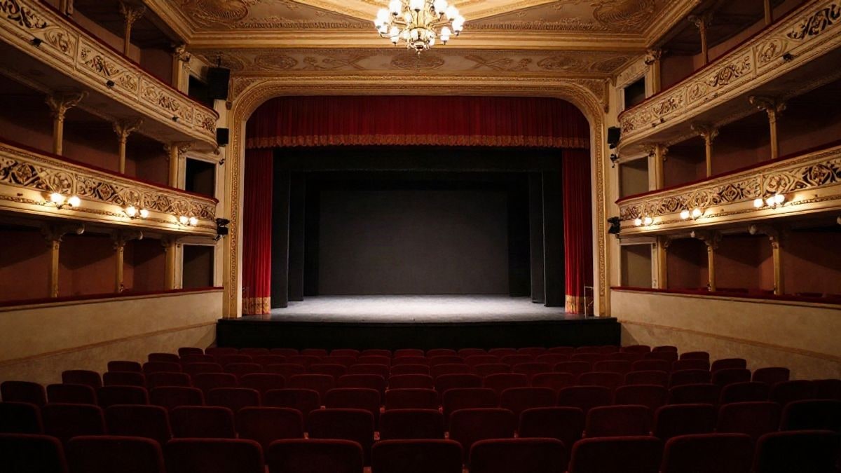 Imagen ilustrativa: escenario de teatro con cortinas rojas y focos