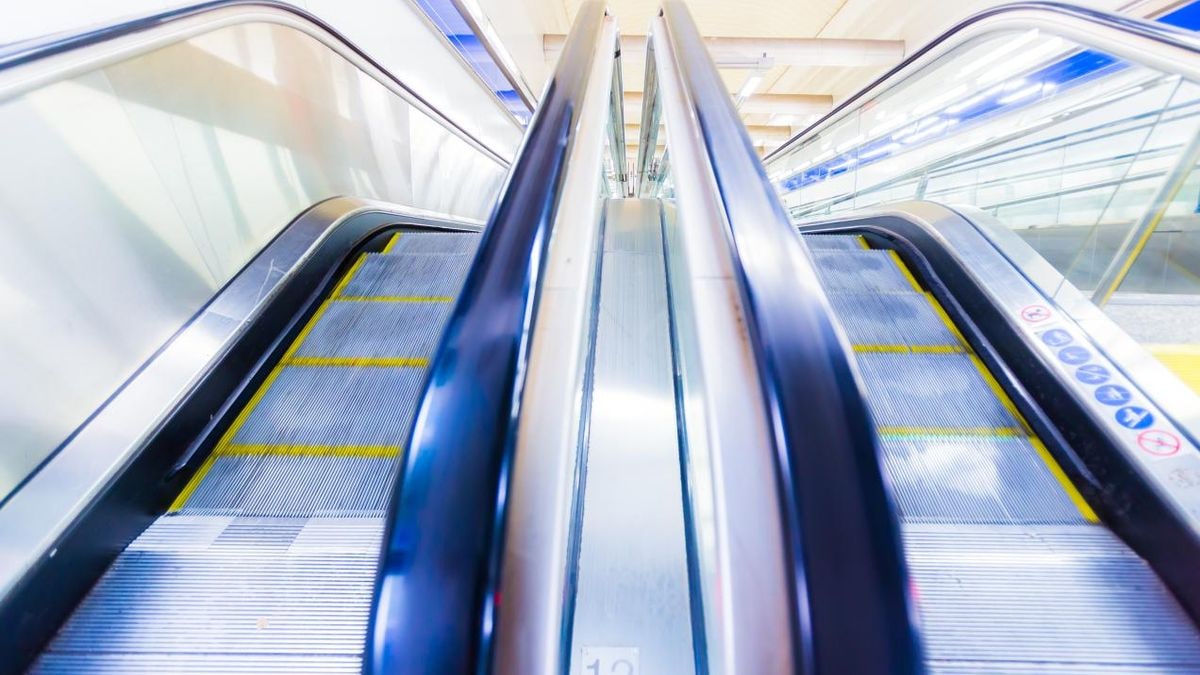 Imagen ilustrativa: escalera mecánica de una estación de metro iluminada de noche con luz artificial cálida