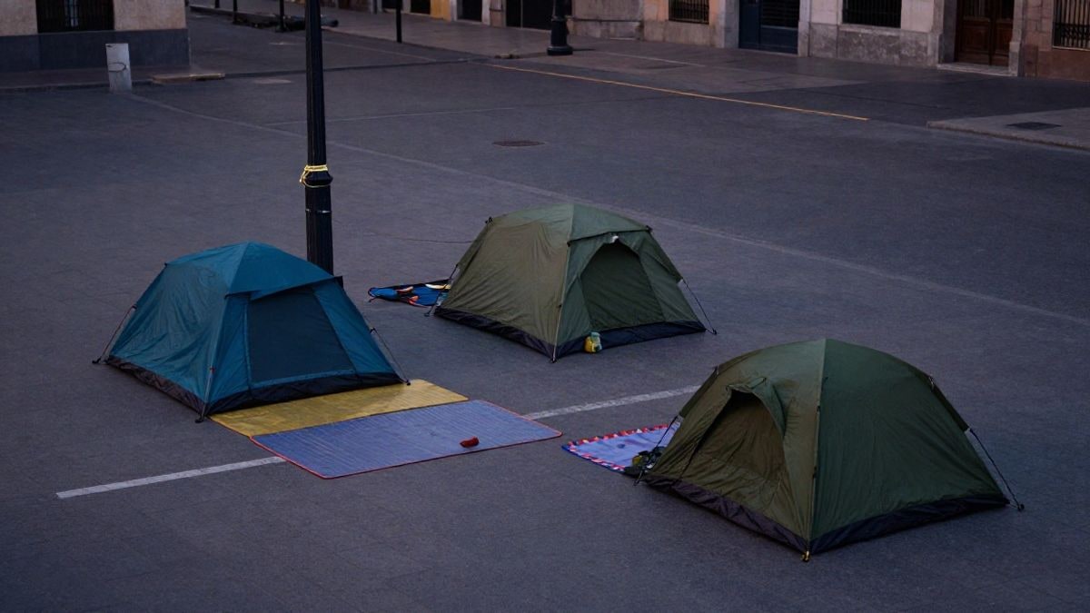 Imagen ilustrativa: vista cenital de una plaza urbana con tiendas de campaña y cuerdas atadas a una farola