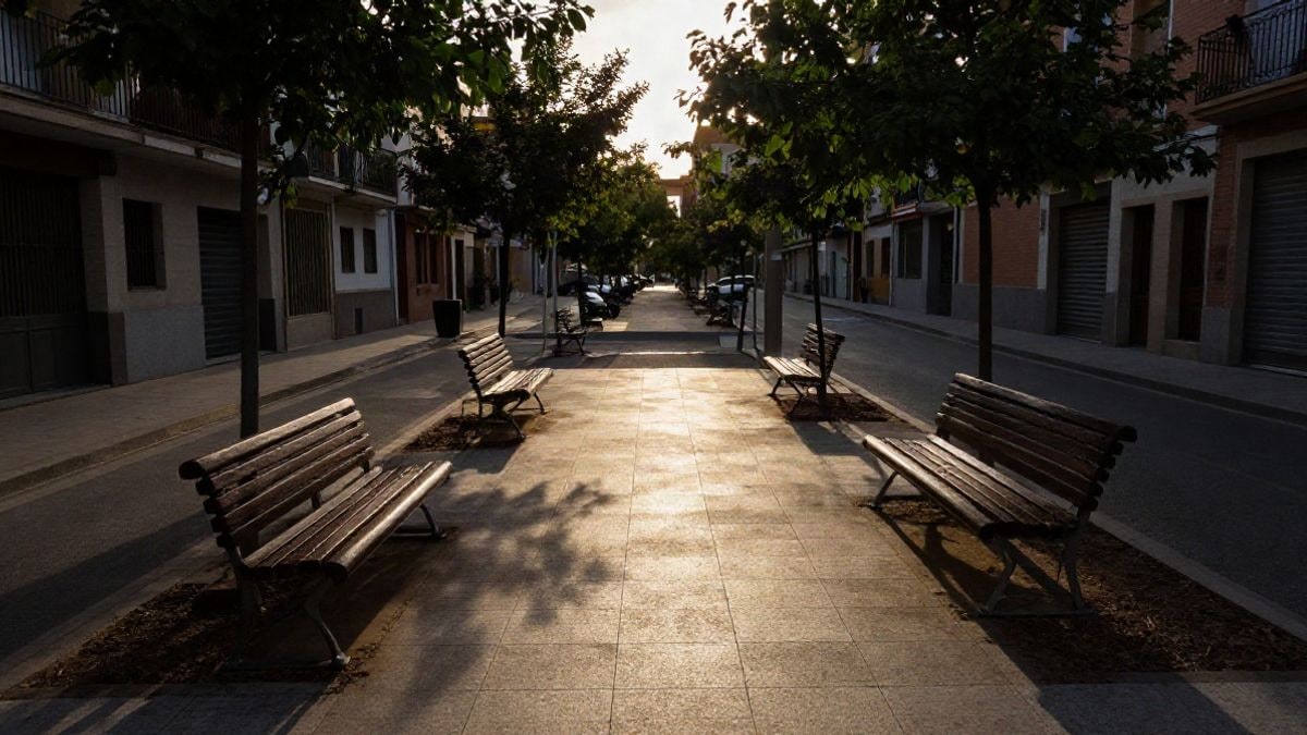 Imagen ilustrativa: calle peatonal reformada con bancos y árboles jóvenes a la luz del atardecer