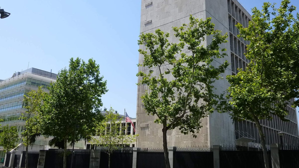 Fachada de la Embajada de Estados Unidos en Madrid con bandera y vallas negras junto a la calle