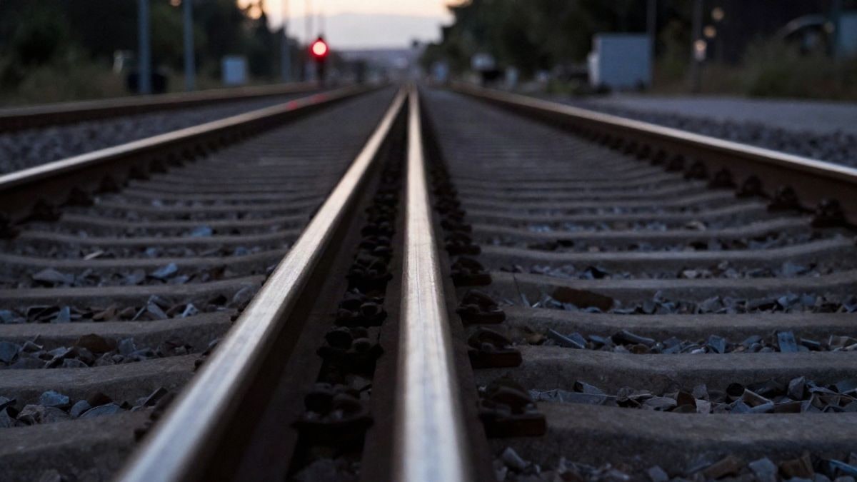 Imagen ilustrativa: vías de ferrocarril al atardecer, con una señal luminosa desenfocada al fondo