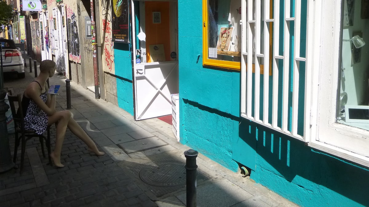 Escaparate de tienda creativa con fachada turquesa en una calle empedrada de Malasaña, Madrid.