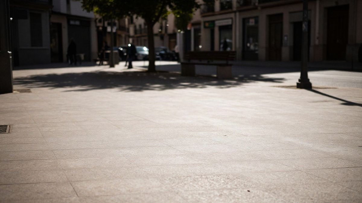 Imagen ilustrativa: calle urbana con pavimento claro y árboles, bajo la luz del sol