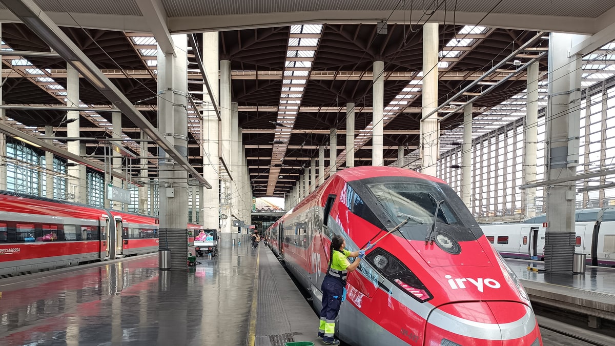 Tren Iryo rojo parado en el andén de Atocha mientras un operario lo limpia