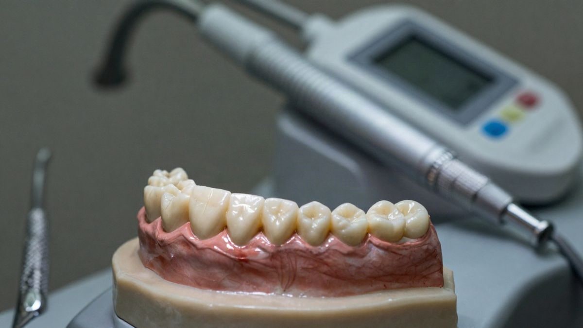 Imagen ilustrativa: modelo de carillas de cerámica sobre una mesa de laboratorio dental con herramientas y escáner digital de fondo.
