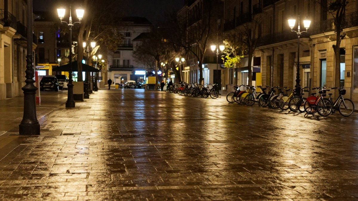 Imagen ilustrativa: una plaza urbana de noche iluminada por farolas y luz cálida sobre el empedrado