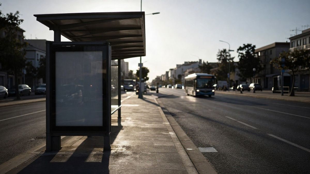 Imagen ilustrativa: parada de autobús urbano al atardecer con marquesina vacía y un autobús desenfocado al fondo