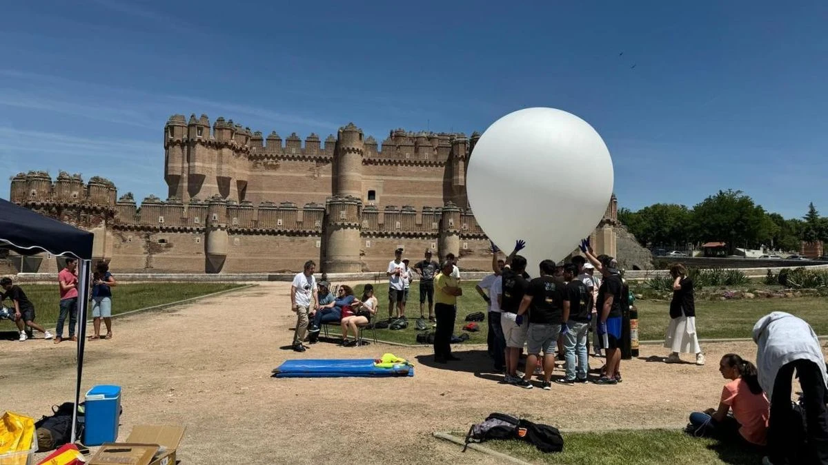 Imagen ilustrativa: un globo sonda ascendiendo al amanecer con un pequeño contenedor de experimentos, contra el cielo azul.
