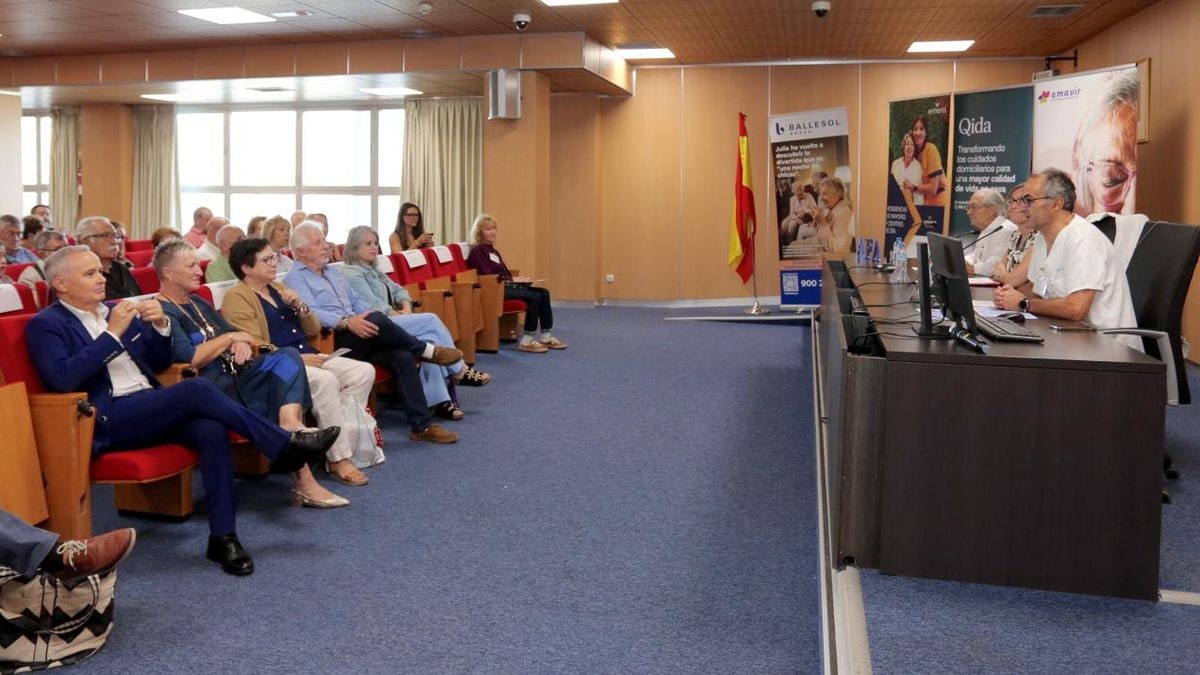Imagen ilustrativa: sala de conferencias vacía con sillas alineadas y mesa con micrófono al atardecer