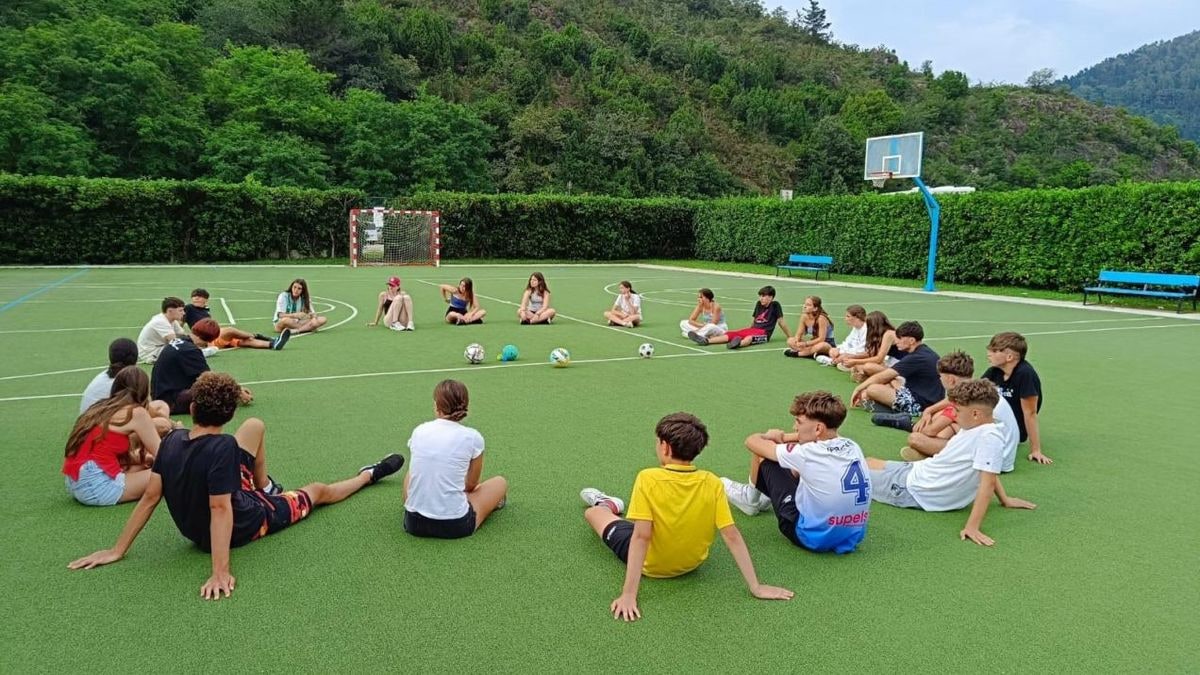 Imagen ilustrativa: un polideportivo escolar vacío con canasta de baloncesto y red de voleibol bajo luz artificial.