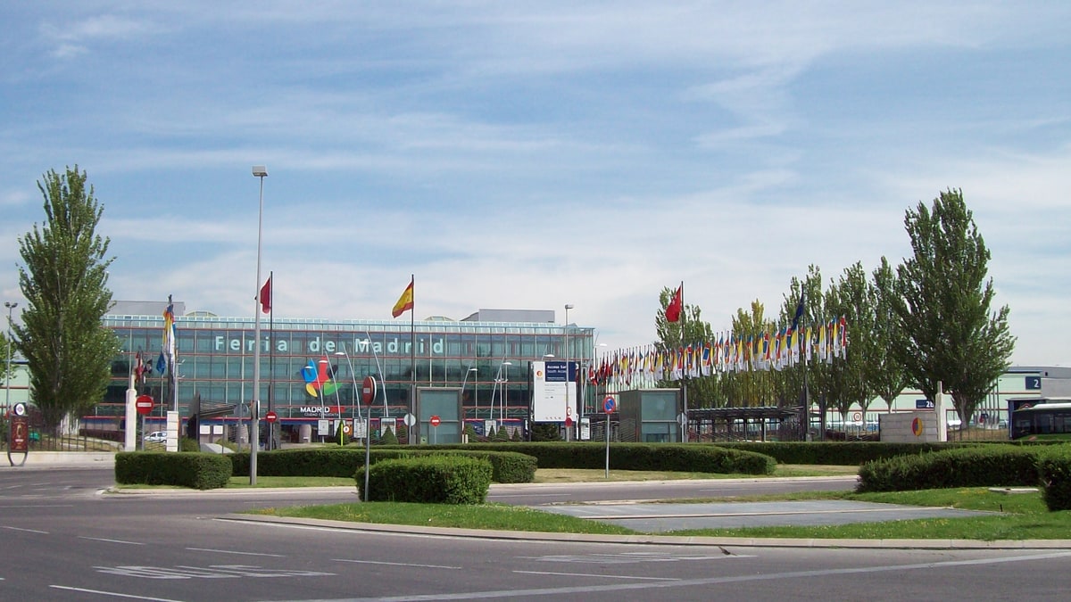 Fachada de cristal del recinto ferial IFEMA con banderas y árboles en el Campo de las Naciones