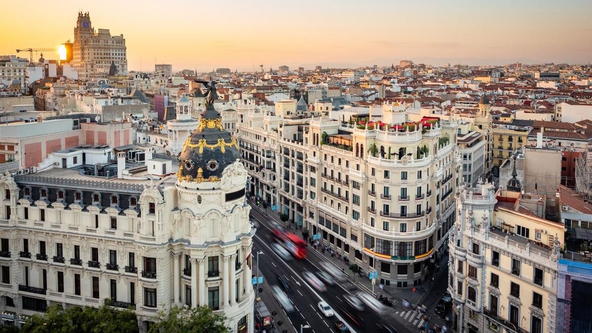 Imagen ilustrativa: siluetas de rascacielos de oficinas a contraluz al atardecer con sombras largas sobre una plaza vacía