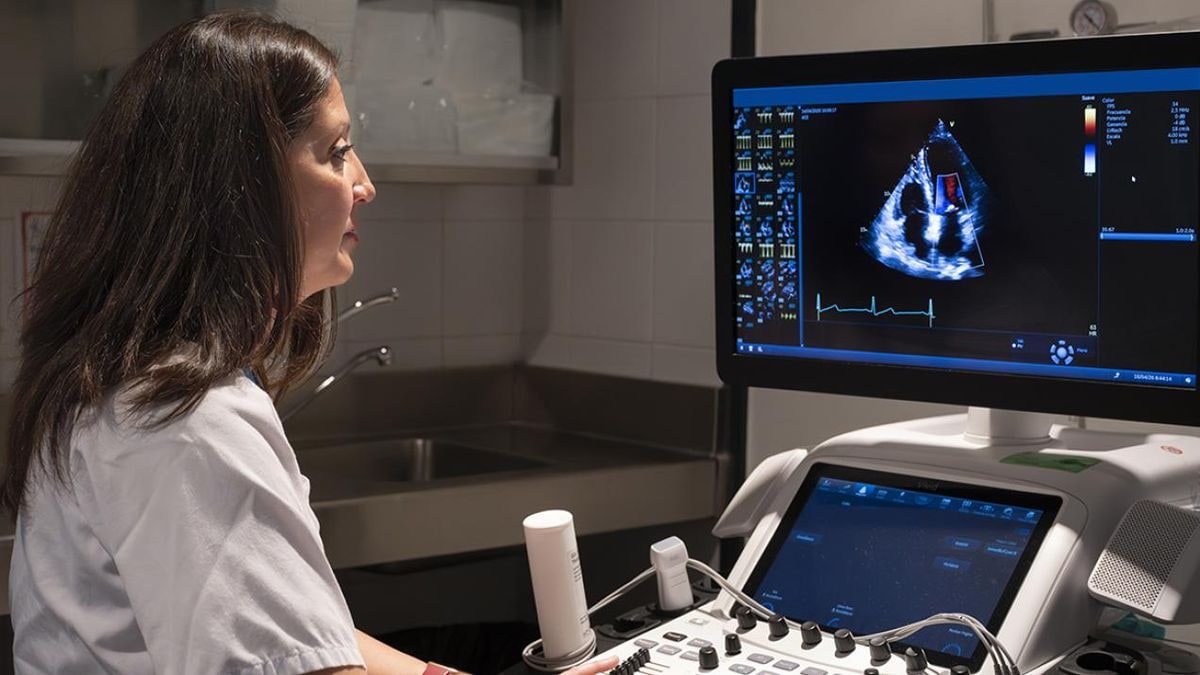 Imagen ilustrativa: monitor de ecocardiografía con una ecografía cardíaca en una sala de hospital en penumbra.