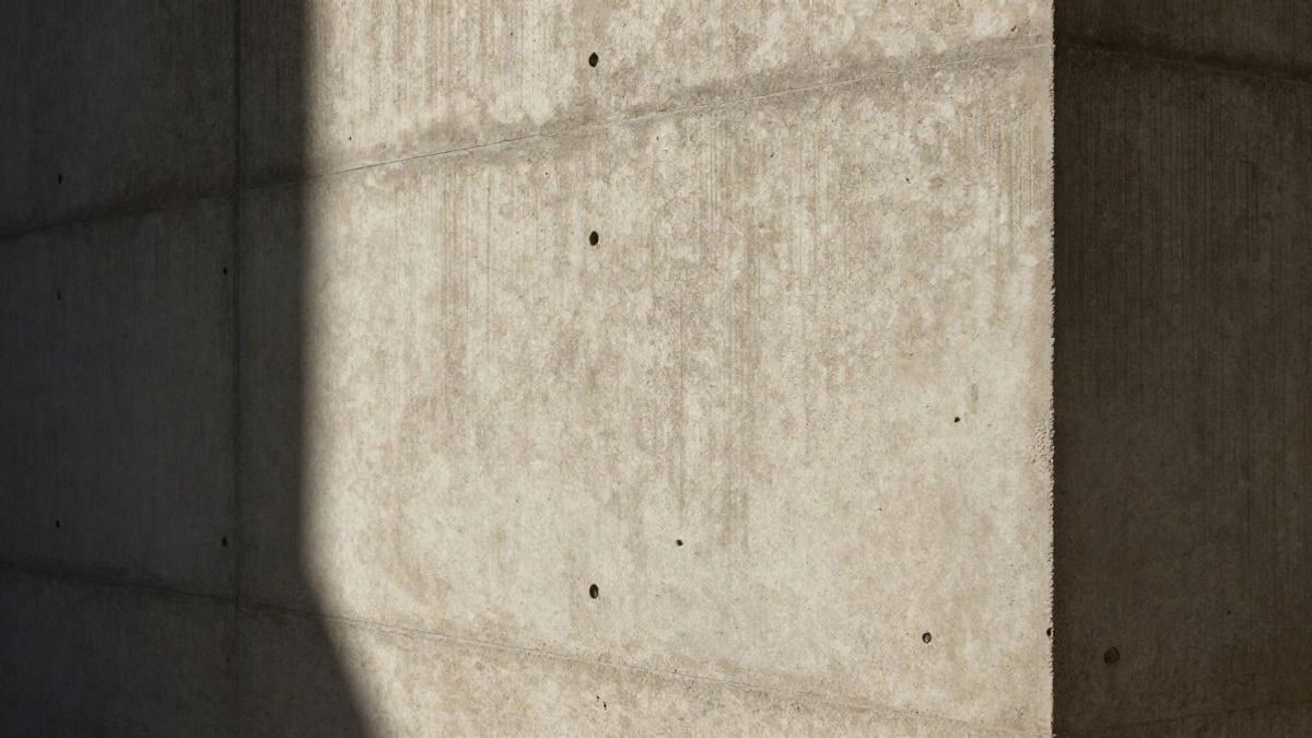 Imagen ilustrativa: detalle de un muro de hormigón armado con textura rugosa y luz rasante