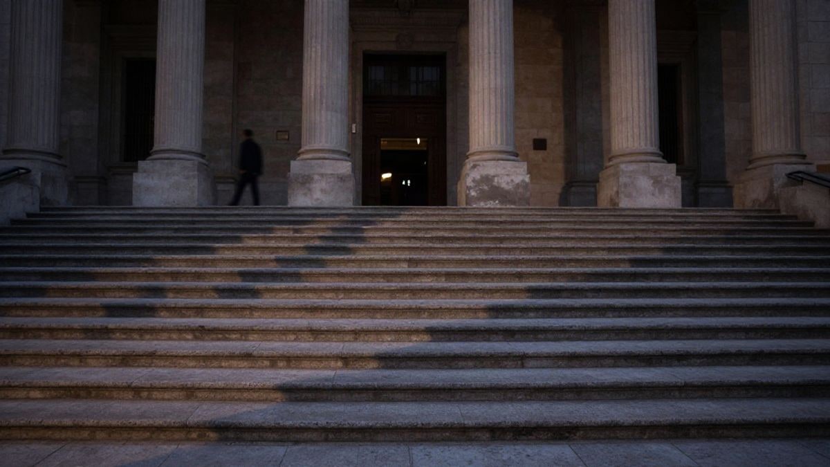 Imagen ilustrativa: entrada genérica de un edificio judicial al atardecer con una figura lejana