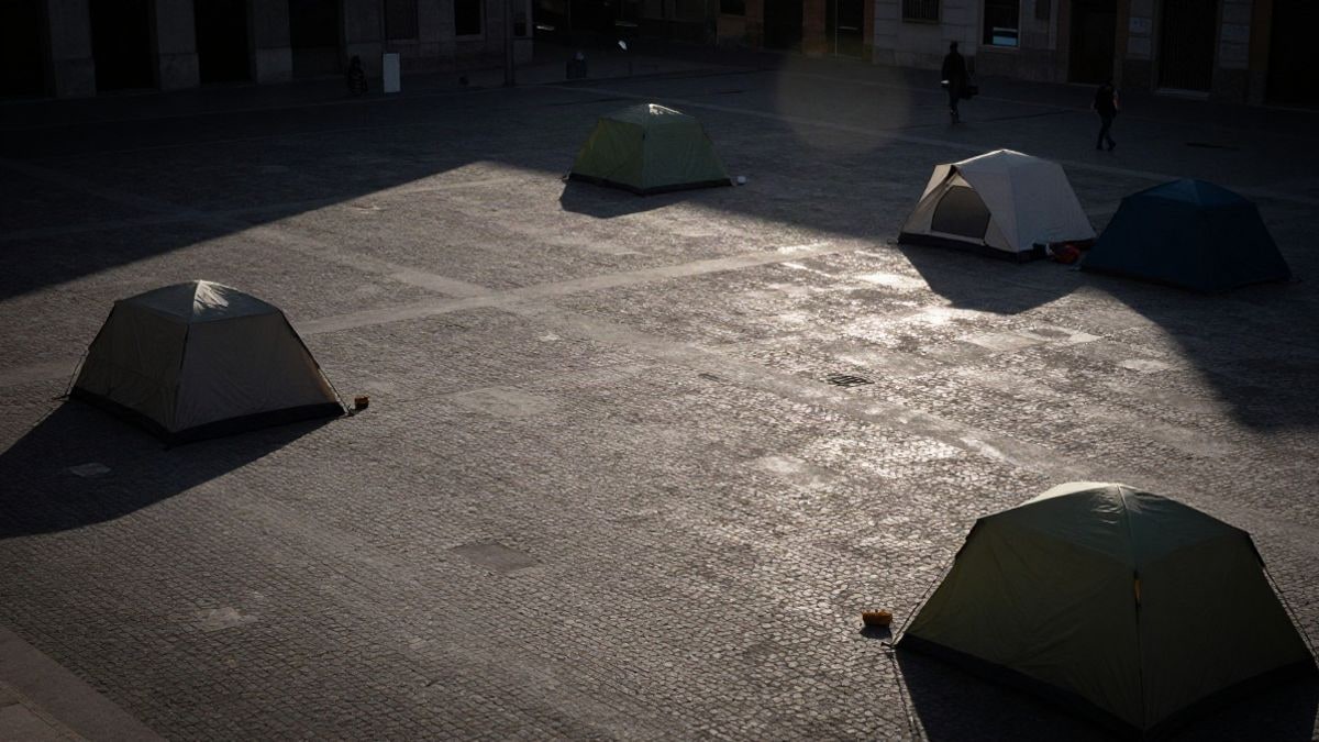 Imagen ilustrativa: vista cenital de una plaza urbana con tiendas de campaña y adoquines, sin personas identificables