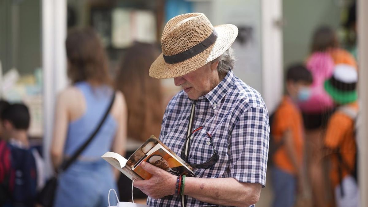Imagen ilustrativa: pila de libros sobre una mesa de madera al aire libre con cielo despejado de fondo