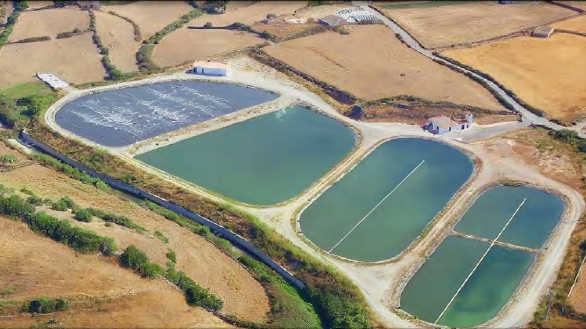 Imagen ilustrativa: vista lateral de una balsa de agua artificial delimitada por diques de tierra en un paisaje seco
