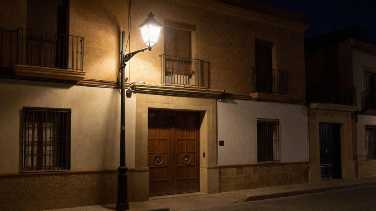 Imagen ilustrativa: portal de un edificio residencial iluminado por una farola en una calle nocturna