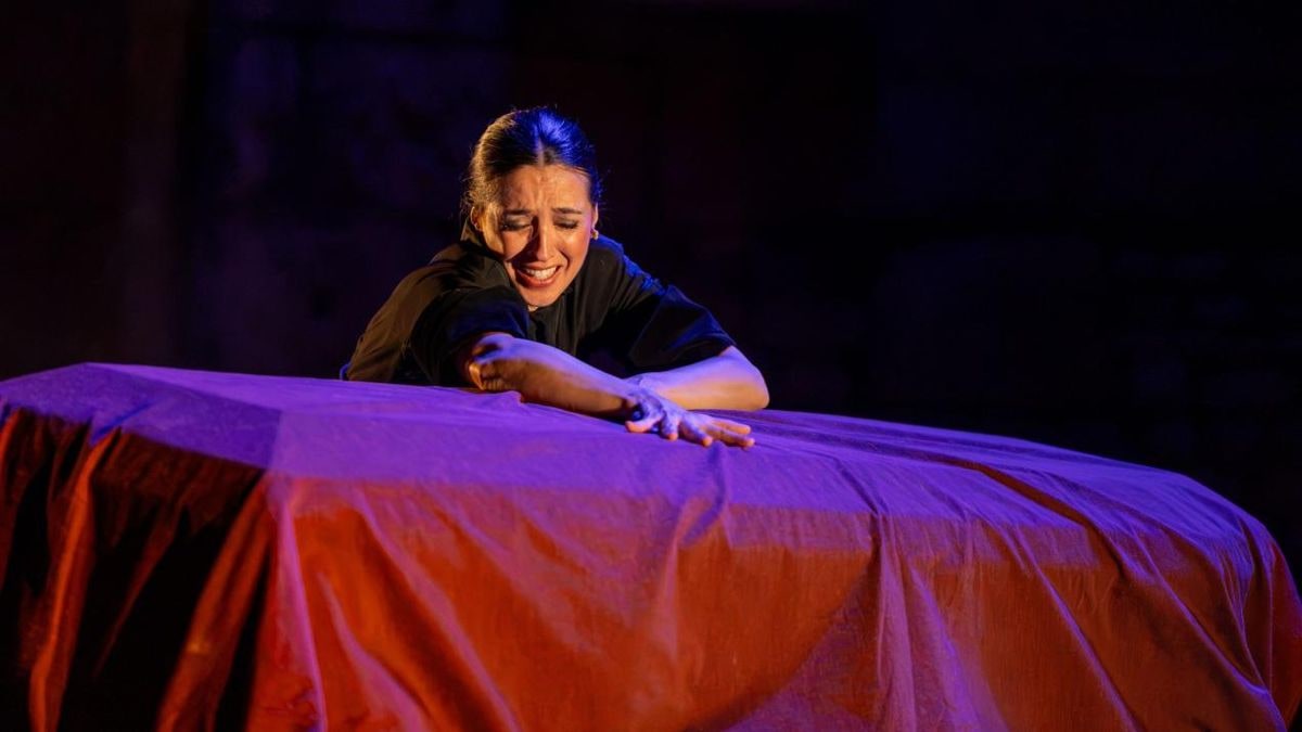 Imagen ilustrativa: escenario de teatro con cortinas rojas y un foco de luz en la oscuridad