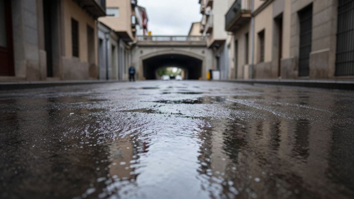 Imagen ilustrativa: calle urbana mojada con grandes charcos y un túnel genérico al fondo tras la lluvia