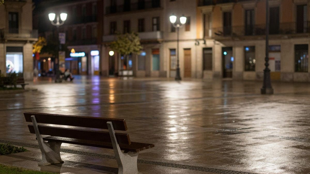 Imagen ilustrativa: plaza urbana vacía de noche, iluminada por farolas y reflejos de luz sobre el pavimento mojado