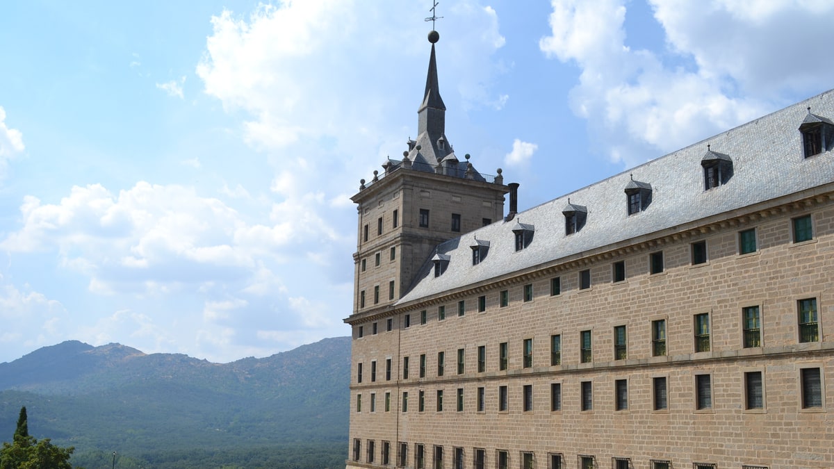 Fachada este del monasterio de El Escorial con su torre y muros de granito bajo cielo azul