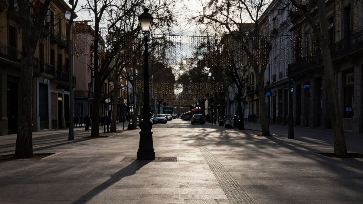 Imagen ilustrativa: avenida urbana al atardecer con guirnaldas navideñas sin encender y sombras largas