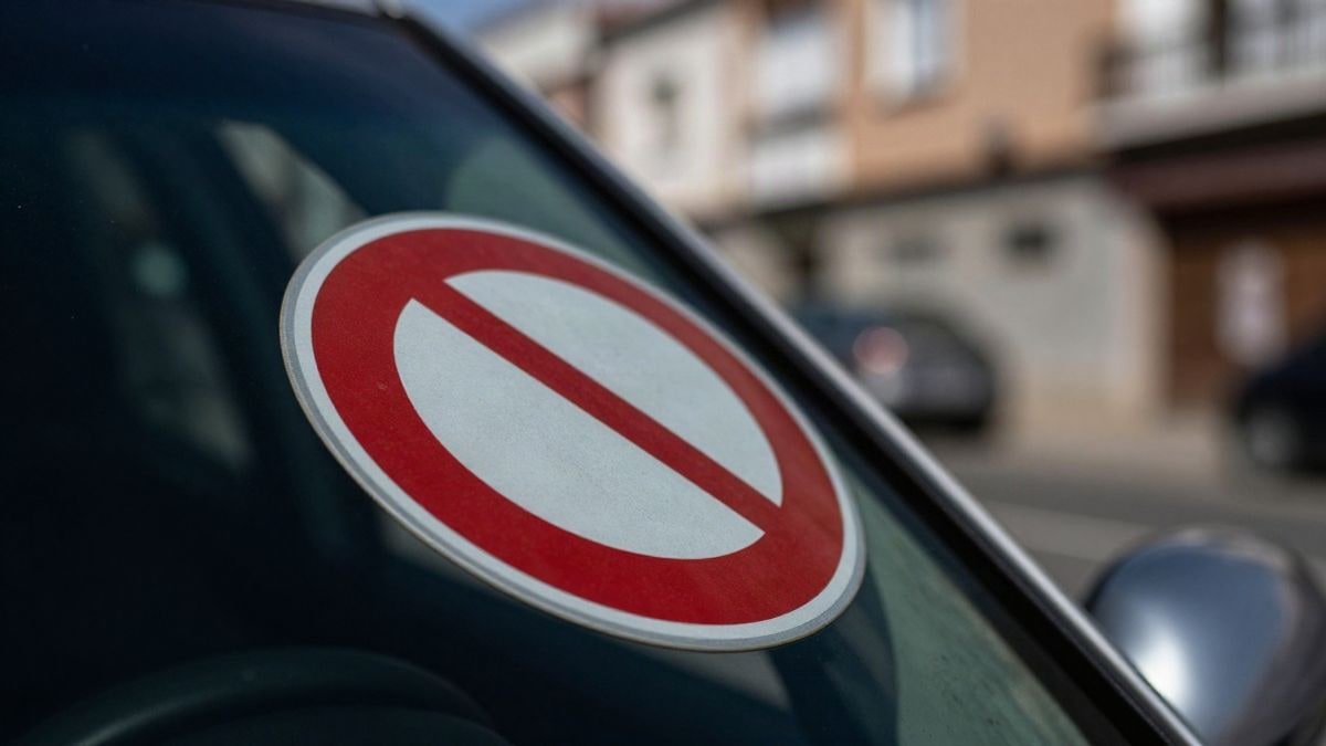 Imagen ilustrativa: una pegatina de acreditación en el parabrisas de un coche, con una calle residencial al fondo.
