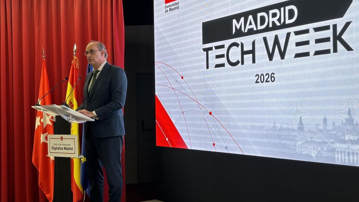 Imagen ilustrativa: escenario de conferencia con pantalla iluminada y asientos vacíos en primer plano