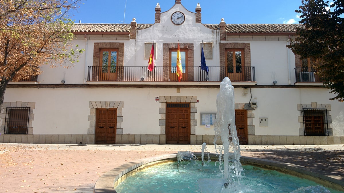 Fachada del Ayuntamiento de Urda con balcón, banderas y fuente en primer plano