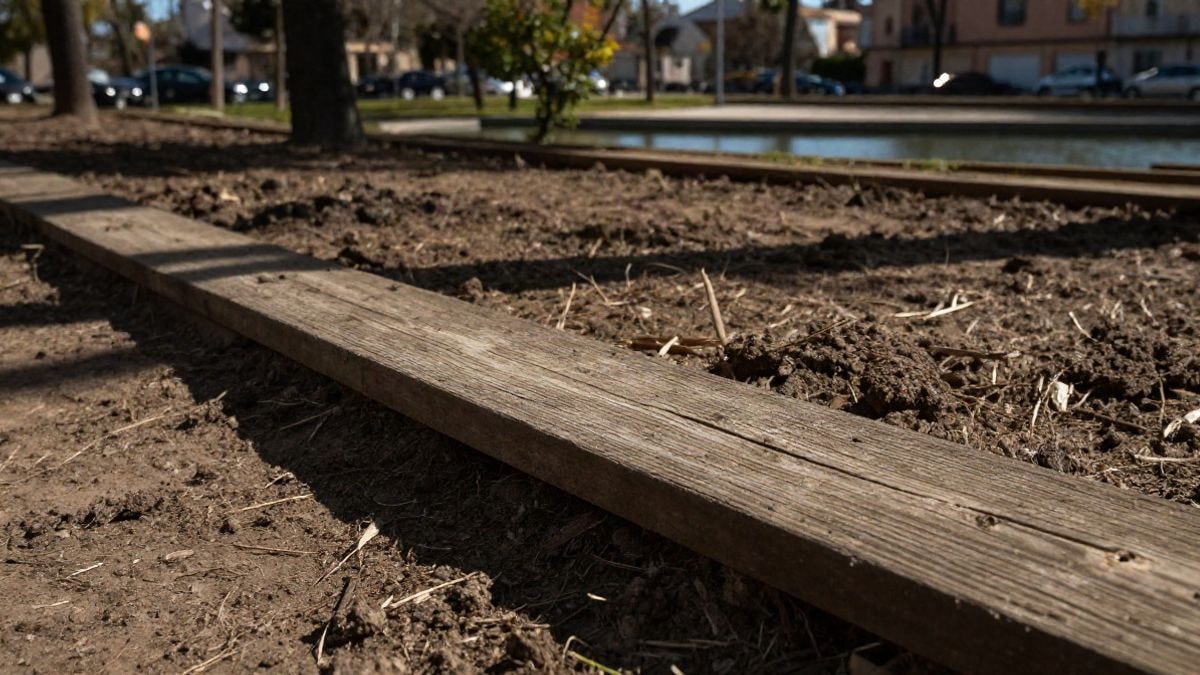 Imagen ilustrativa: detalle de tablones de madera y tierra en un parque recién plantado con una laguna al fondo