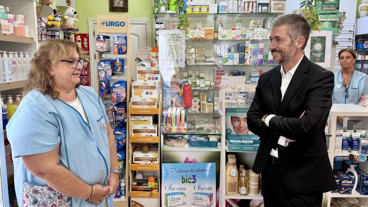 Imagen ilustrativa: fachadas de farmacias en un pueblo al atardecer con luz cálida en los escaparates