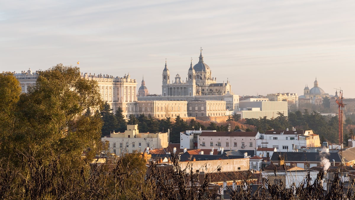 Catedral de la Almudena y Palacio Real de Madrid vistos desde el oeste al atardecer, con tejados en primer plano.