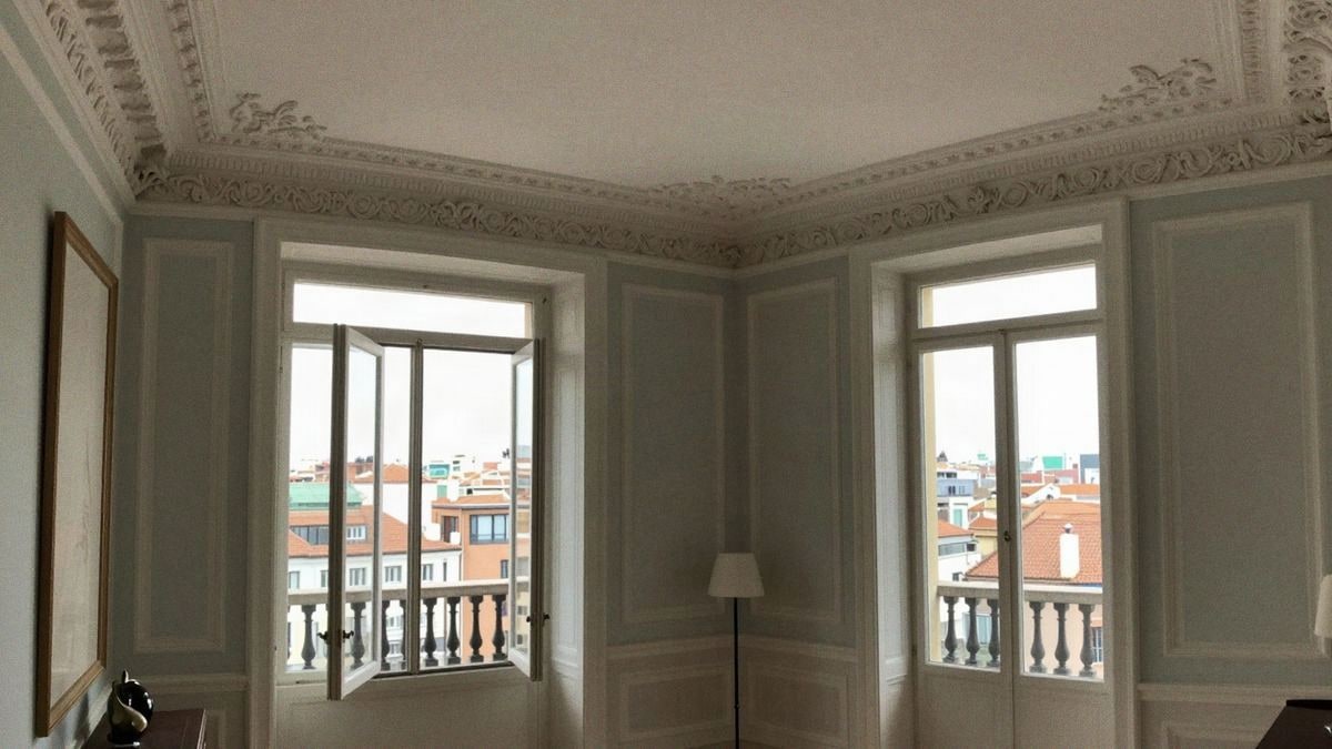 Interior de un lujoso apartamento en Madrid con techos altos, detalles arquitectónicos elegantes y vistas a la ciudad.