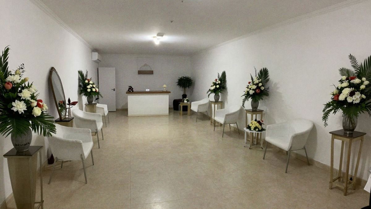 Interior de un tanatorio con salas amplias, arreglos florales elegantes y luz suave, transmitiendo calma y respeto.