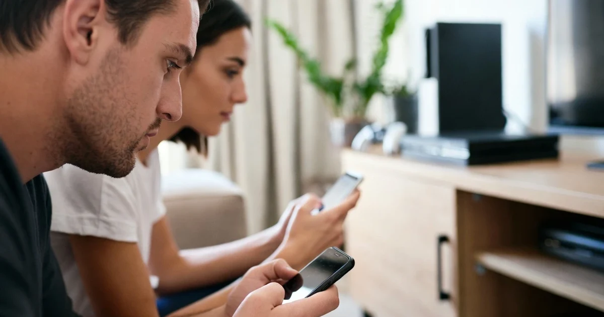 Adultos jugando a videojuegos en el móvil en un salón.